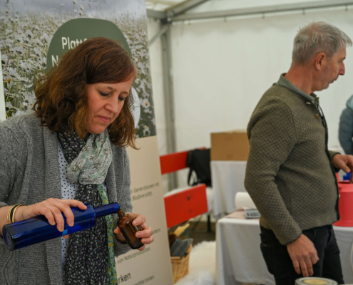 Frau füllt Flüssigkeit um, Infostand zur Inklusion und Teilhabe beim Wildgehölztag Salzburg
