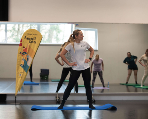 Sportkurs im Tanzstudio mit Trainerin und Teilnehmenden, Fokus auf Inklusion und Gesundheit