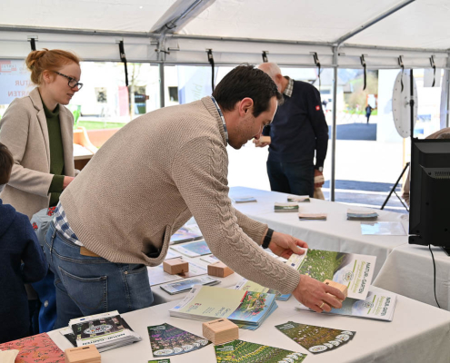 Menschen informieren sich an Infostand mit Flyern zu Inklusion, Teilhabe und sozialen Projekten