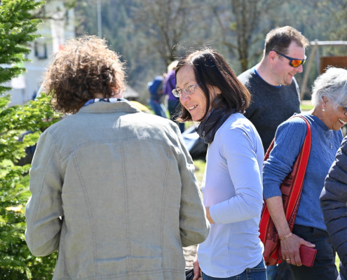 Mehrere Menschen unterhalten sich lachend draußen bei Sonnenschein, soziale Teilhabe Inklusion