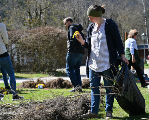 Mehrere Personen sammeln Äste und Müll im Park, Inklusion und Engagement in Salzburg