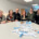Team des Sozialunternehmens und Team vom AMS Salzburg vor dem Modell des Kreativraums.