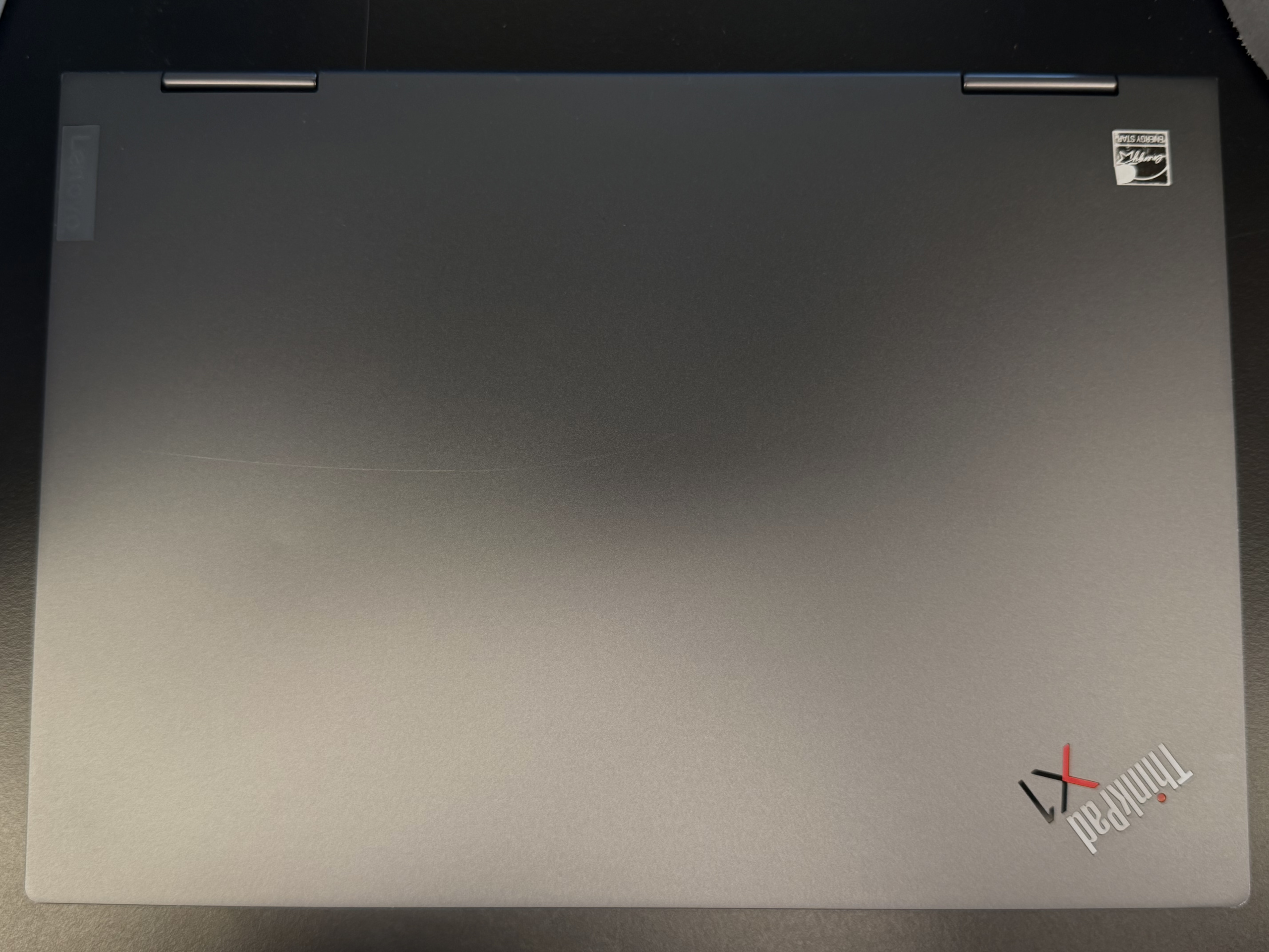 Grauer Laptop mit ThinkPad-Logo auf dunkler Tischfläche